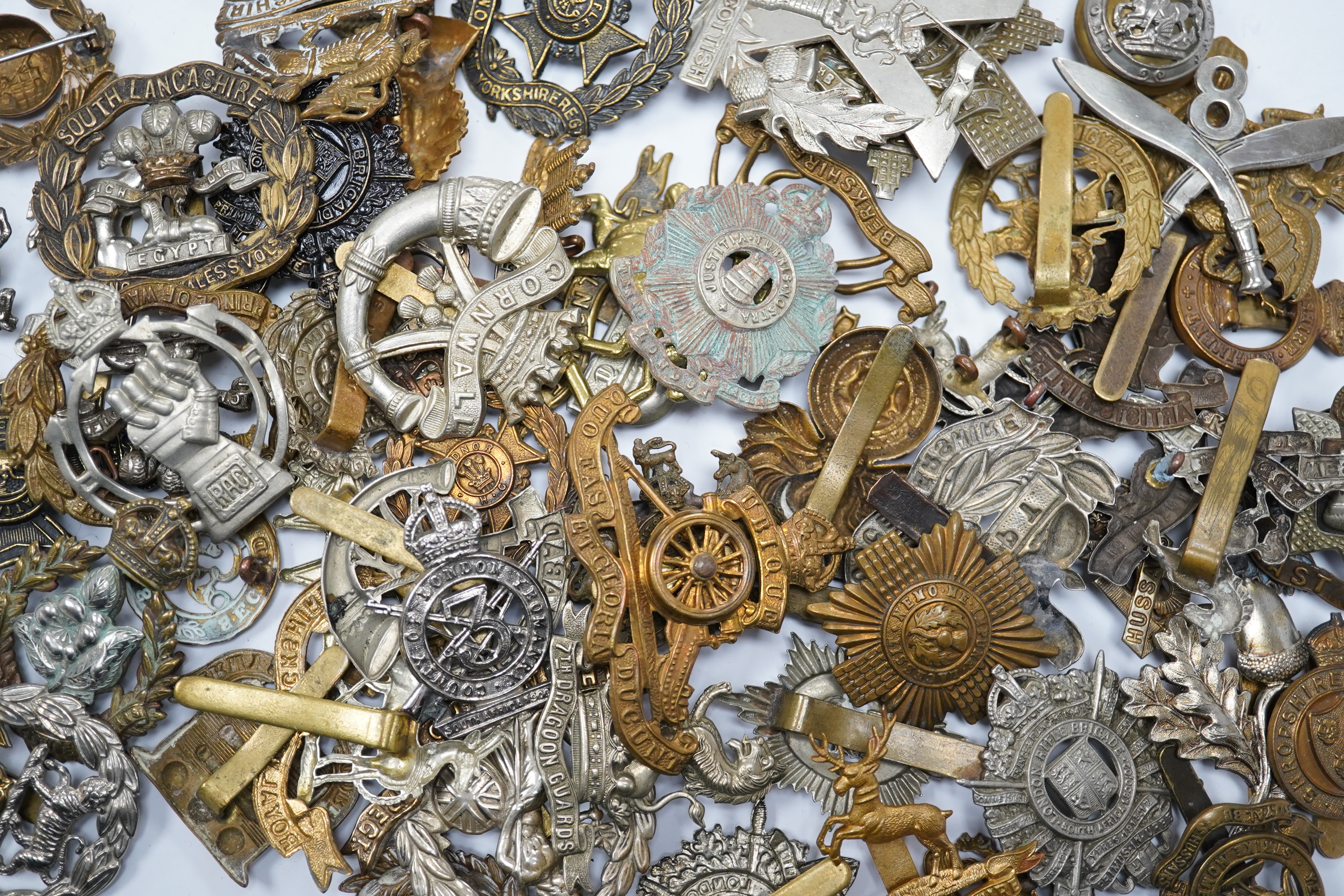 Sixty military cap badges, including; the Hampshire regiment, the South Lancashire Regiment, Prince of Wales Volunteers, the Tyneside Scottish Regiment, the Royal Artillery, the Norfolk Regiment, the Army Ordinance Corps